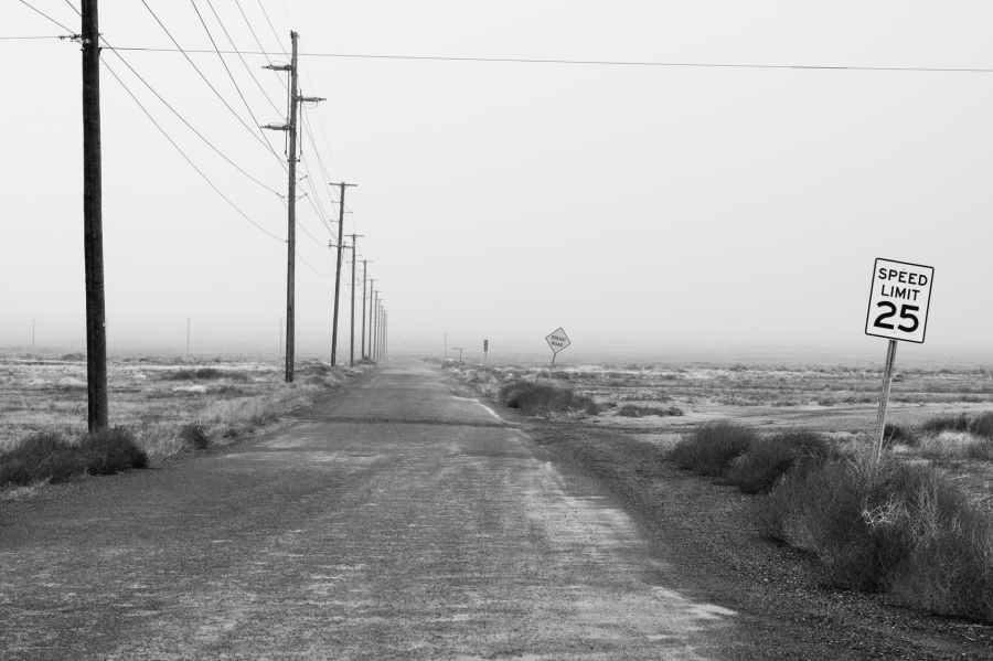 monochrome photography of an empty road with speed limit sign